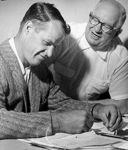 Gordie Howe signs his contract with the Detroit Red Wings in August of 1959, as Jack Adams looks on.