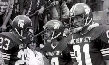 Kirk Gibson (#23) with two teammates on the sidelines at Michigan State University.